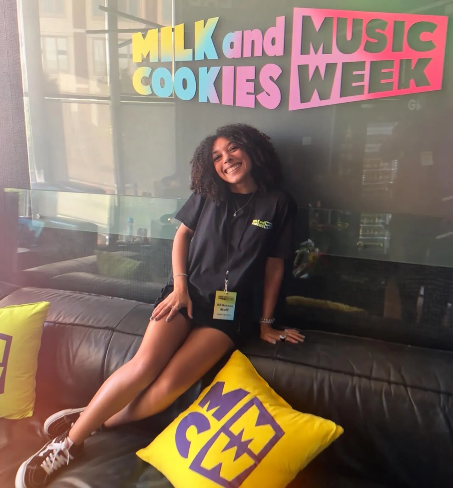 Woman seated beneath a Milk and Music Cookies Week sign