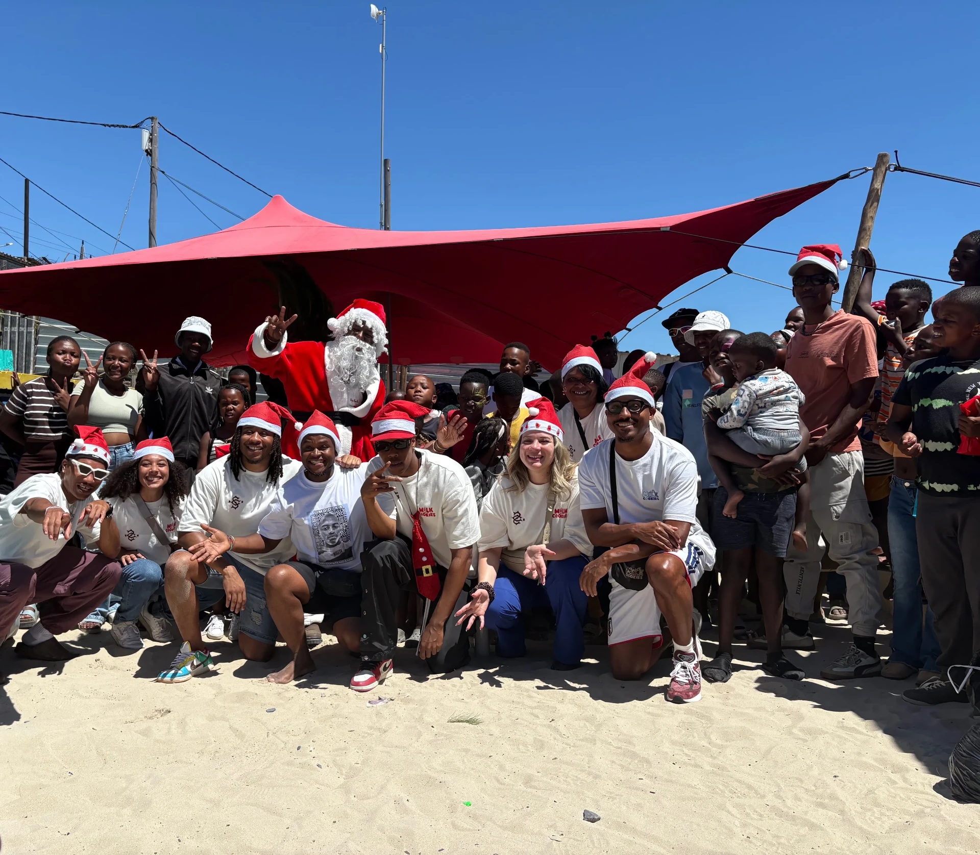 Community event group with Santa beneath a red canopy