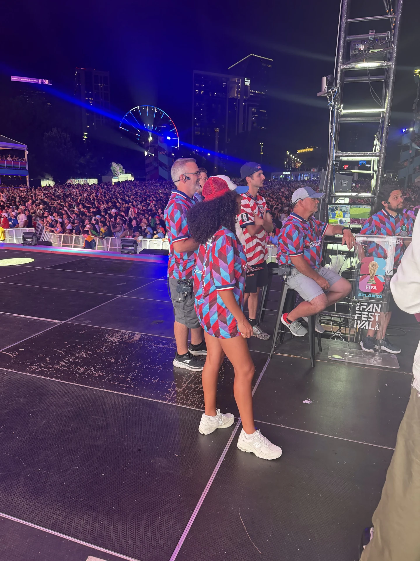 Event staff beside the FIFA Fan Festival Atlanta stage at night